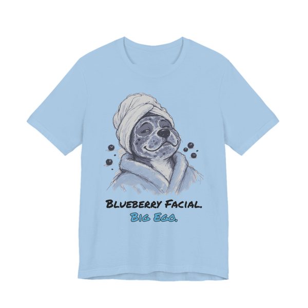 Baby Blue t-shirt printed in full-color print with a full-color pencil drawing of a dog in a towel and bathrobe with blueberries around it and the words “Blueberry Facial. Big Ego.”