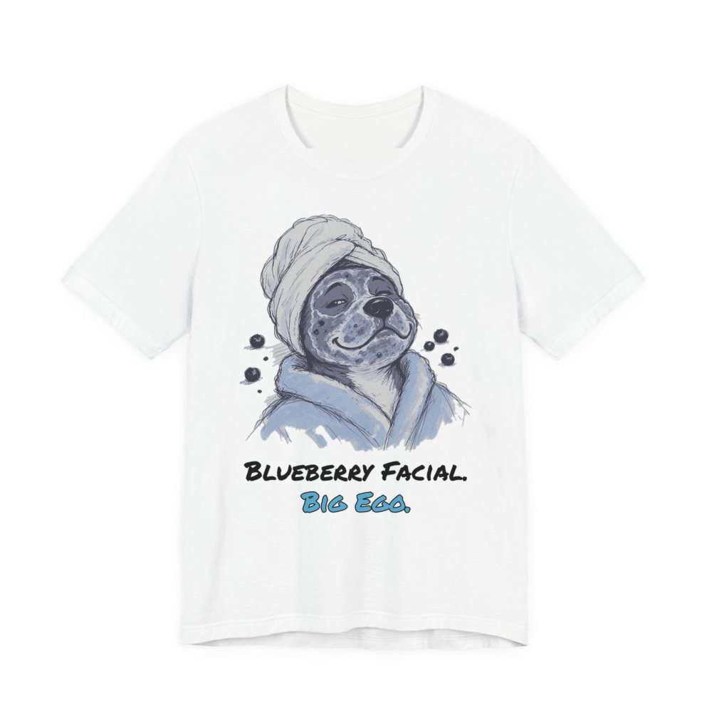White t-shirt printed in full-color print with a full-color pencil drawing of a dog in a towel and bathrobe with blueberries around it and the words “Blueberry Facial. Big Ego.”