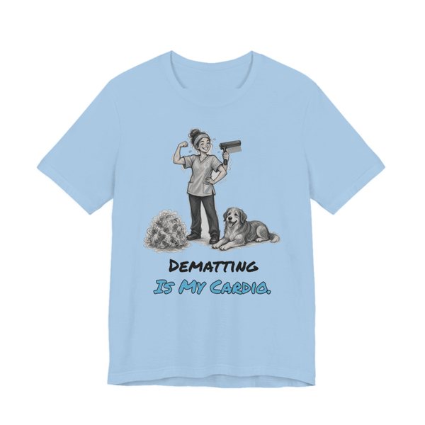 Baby Blue t-shirt printed in full-color print with a full-color pencil drawing of a groomer flexing with a dryer next to a dog and a pile of fur and the words “Dematting Is My Cardio.”
