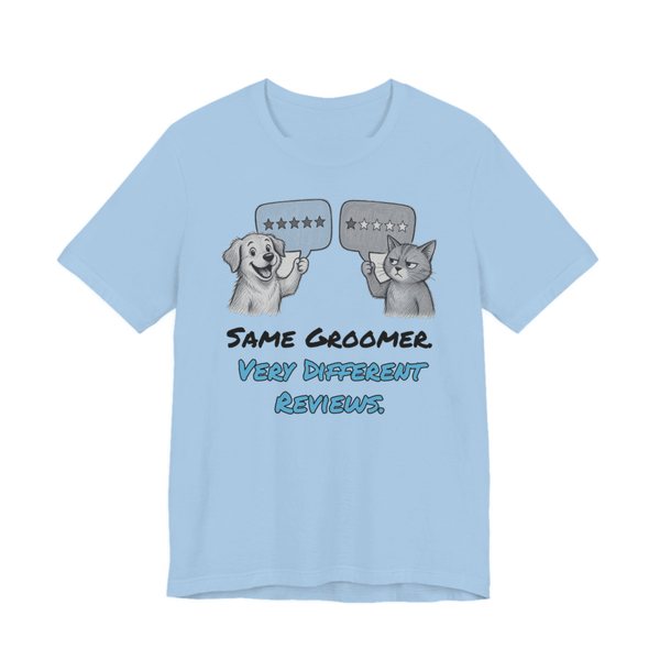 Baby Blue t-shirt printed in full-color print with a full-color pencil drawing of a dog holding a five-star review and a cat holding a one-star review and the words “Same Groomer. Very Different Reviews.”