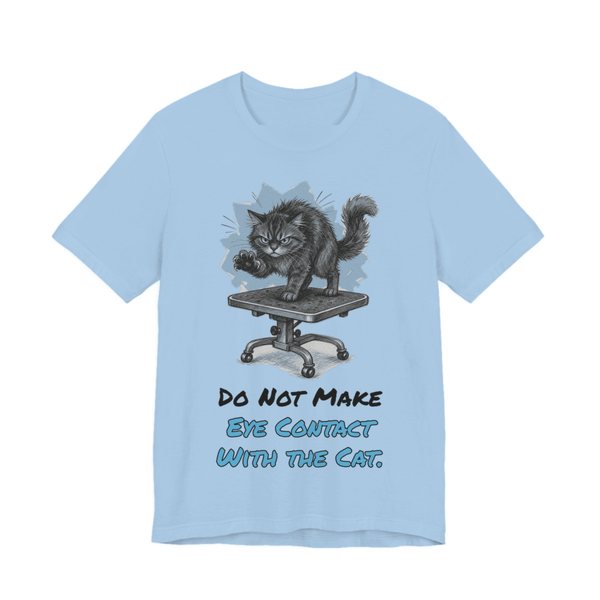Baby Blue t-shirt printed in full-color print with a full-color pencil drawing of an angry cat on a grooming table and the words “Do Not Make Eye Contact With the Cat.”