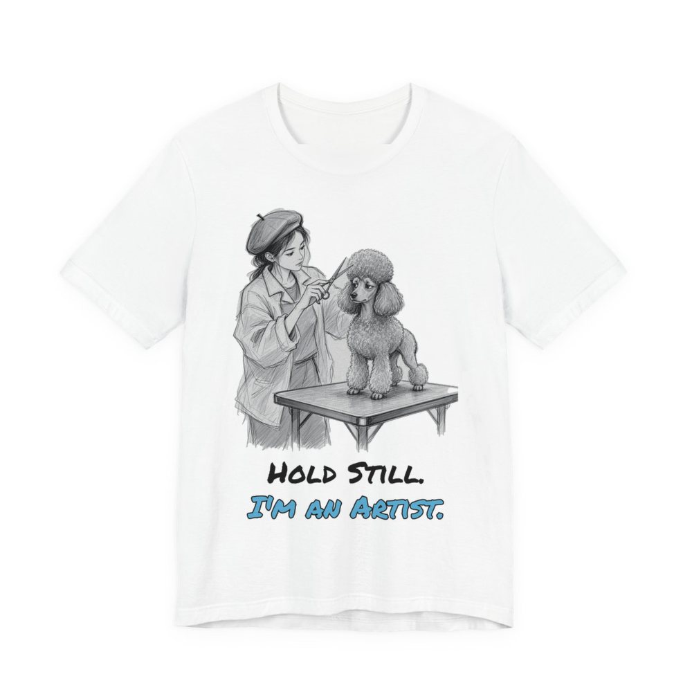 White t-shirt printed in full-color print with a full-color pencil drawing of a groomer in a beret sculpting a poodle cut and the words “Hold Still. I'm an Artist.”