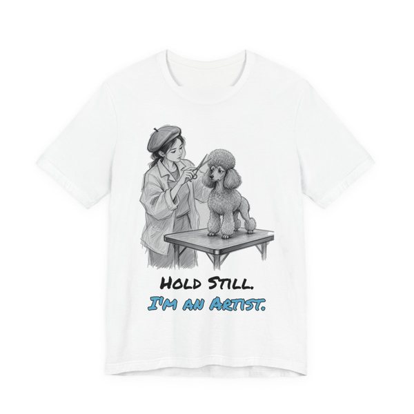 White t-shirt printed in full-color print with a full-color pencil drawing of a groomer in a beret sculpting a poodle cut and the words “Hold Still. I'm an Artist.”