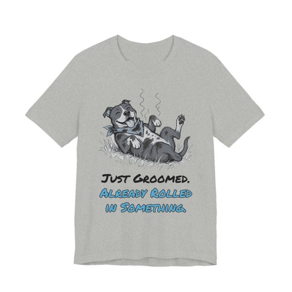 Athletic Heather t-shirt printed in full-color print with a full-color pencil drawing of a freshly groomed pit bull with a bandana rolling in the grass and the words “Just Groomed. Already Rolled in Something.”