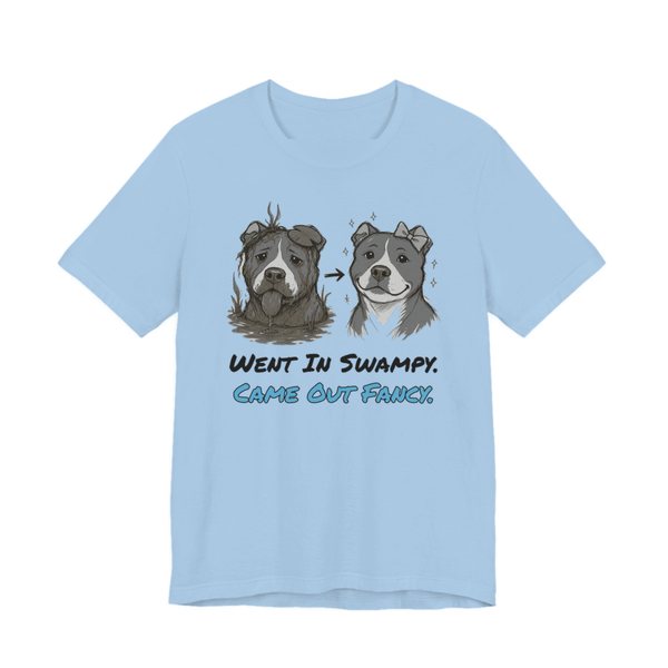 Baby Blue t-shirt printed in full-color print with a full-color pencil drawing of a muddy pit bull next to the same pit bull freshly groomed and the words “Went In Swampy. Came Out Fancy.”