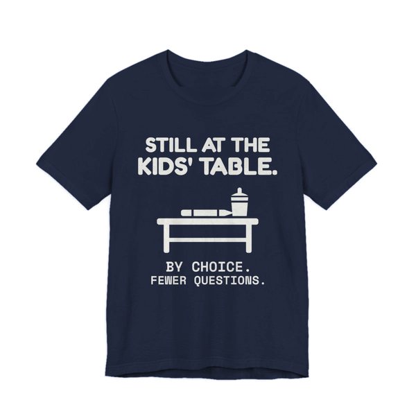 Navy t-shirt printed in off-white ink with the words “Still at the Kids' Table.”