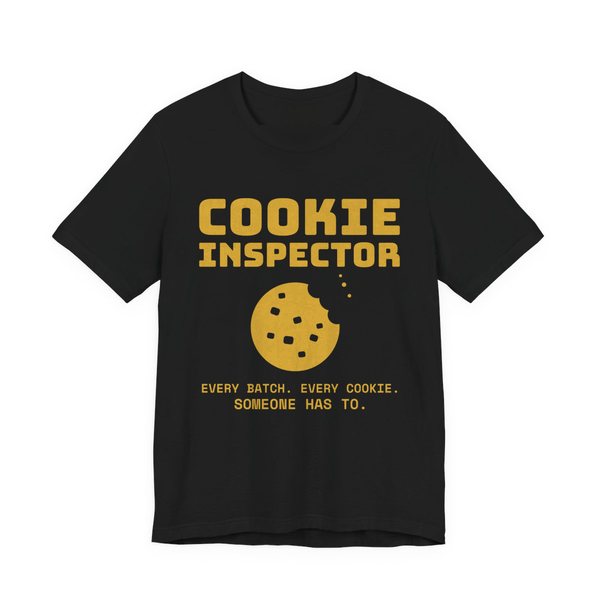 Black t-shirt printed in gold ink with a bitten cookie and the words “Cookie Inspector. Every batch. Every cookie. Someone has to.”