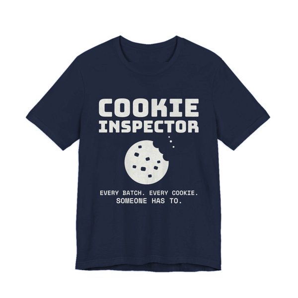 Navy t-shirt printed in off-white ink with a bitten cookie and the words “Cookie Inspector. Every batch. Every cookie. Someone has to.”