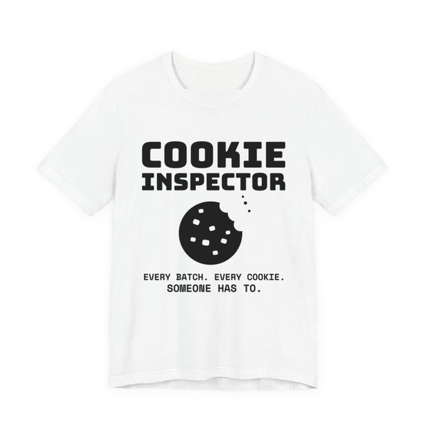 White t-shirt printed in dark ink with a bitten cookie and the words “Cookie Inspector. Every batch. Every cookie. Someone has to.”