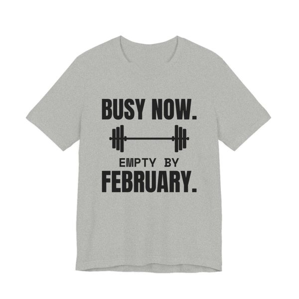 Athletic Heather t-shirt printed in dark ink with a barbell and the words “Busy Now. Empty by February.”