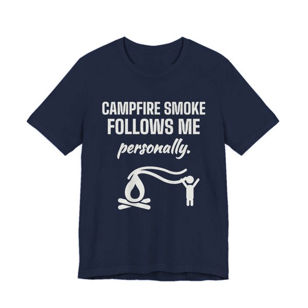 Navy t-shirt printed in off-white ink with a campfire whose smoke trails after a little stick figure and the words “Campfire Smoke Follows Me Personally.”
