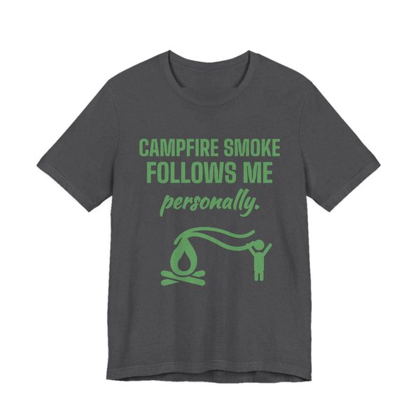 Dark Grey Heather t-shirt printed in pine green ink with a campfire whose smoke trails after a little stick figure and the words “Campfire Smoke Follows Me Personally.”