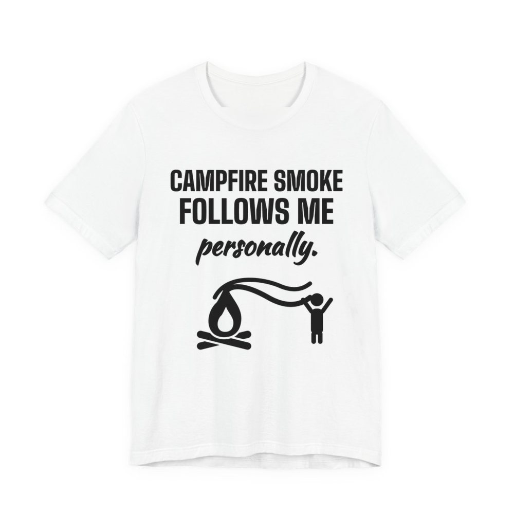 White t-shirt printed in dark ink with a campfire whose smoke trails after a little stick figure and the words “Campfire Smoke Follows Me Personally.”