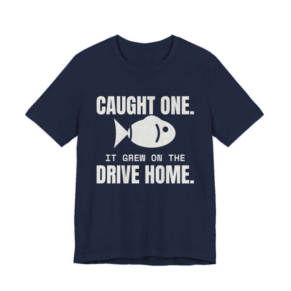 Navy t-shirt printed in off-white ink with a fish and the words “Caught One. It Grew on the Drive Home.”