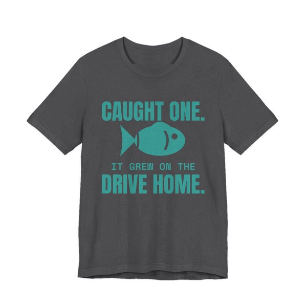 Dark Grey Heather t-shirt printed in teal ink with a fish and the words “Caught One. It Grew on the Drive Home.”