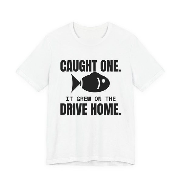 White t-shirt printed in dark ink with a fish and the words “Caught One. It Grew on the Drive Home.”