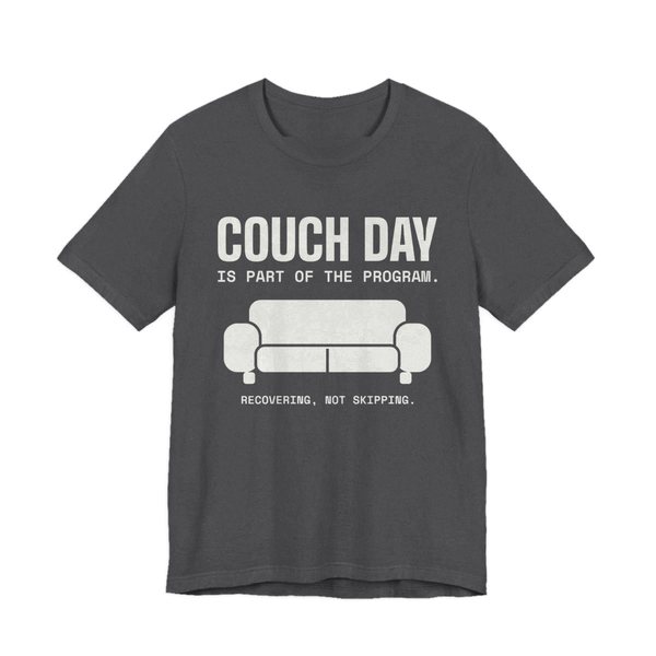 Dark Grey Heather t-shirt printed in off-white ink with a couch and the words “Couch Day Is Part of the Program. Recovering, Not Skipping.”