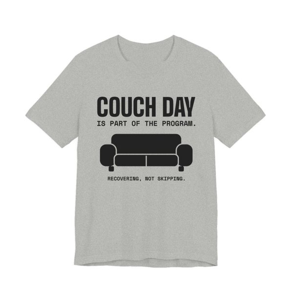 Athletic Heather t-shirt printed in dark ink with a couch and the words “Couch Day Is Part of the Program. Recovering, Not Skipping.”