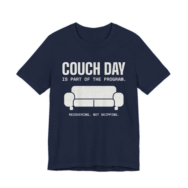 Navy t-shirt printed in off-white ink with a couch and the words “Couch Day Is Part of the Program. Recovering, Not Skipping.”