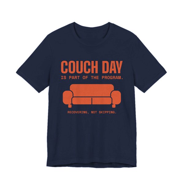 Navy t-shirt printed in orange ink with a couch and the words “Couch Day Is Part of the Program. Recovering, Not Skipping.”