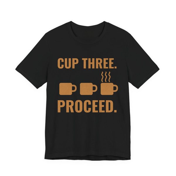 Black t-shirt printed in caramel ink with a row of mugs, the last one steaming, and the words “Cup Three. Proceed.”