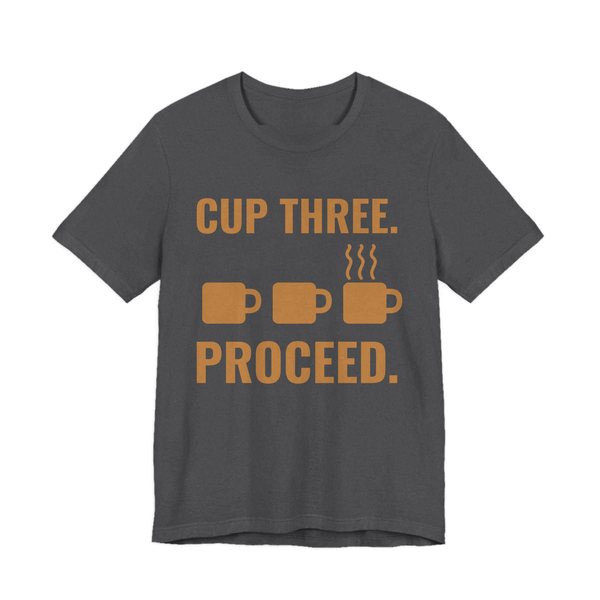 Dark Grey Heather t-shirt printed in caramel ink with a row of mugs, the last one steaming, and the words “Cup Three. Proceed.”
