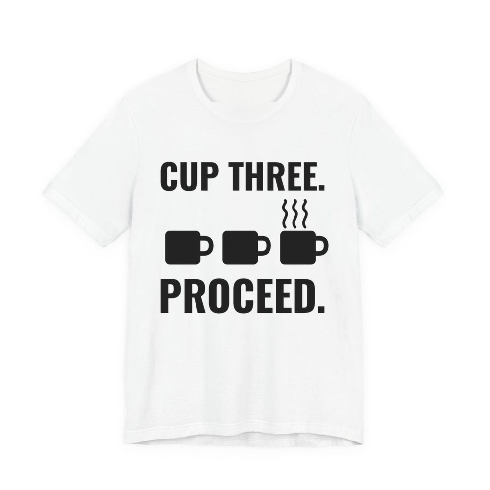 White t-shirt printed in dark ink with a row of mugs, the last one steaming, and the words “Cup Three. Proceed.”