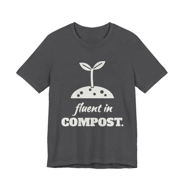 Dark Grey Heather t-shirt printed in off-white ink with a sprout in a mound of soil and the words “Fluent in Compost.”