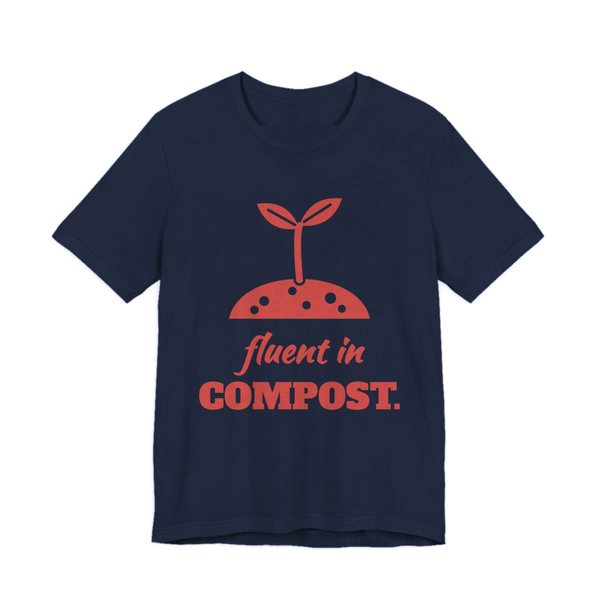 Navy t-shirt printed in tomato red ink with a sprout in a mound of soil and the words “Fluent in Compost.”