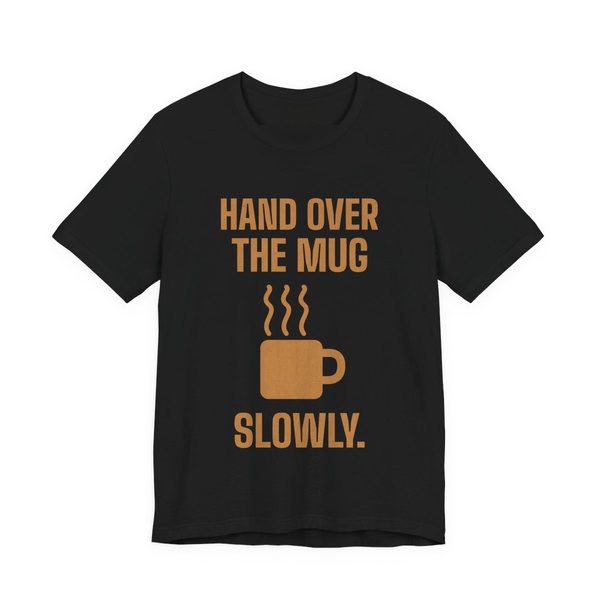Black t-shirt printed in caramel ink with a steaming mug and the words “Hand Over the Mug Slowly.”