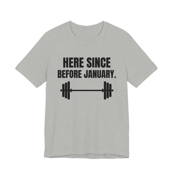 Athletic Heather t-shirt printed in dark ink with a barbell and the words “Here Since Before January.”