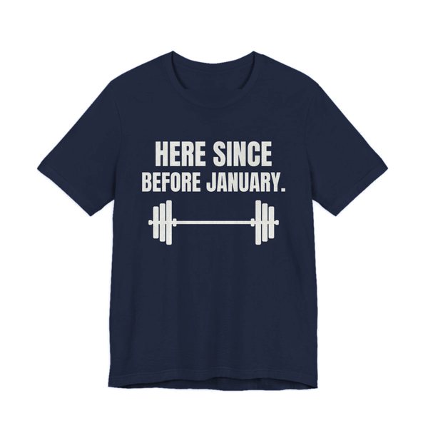 Navy t-shirt printed in off-white ink with a barbell and the words “Here Since Before January.”