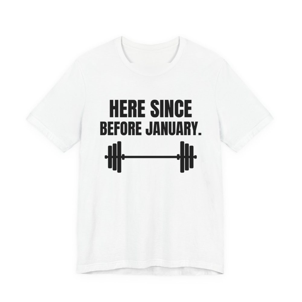 White t-shirt printed in dark ink with a barbell and the words “Here Since Before January.”