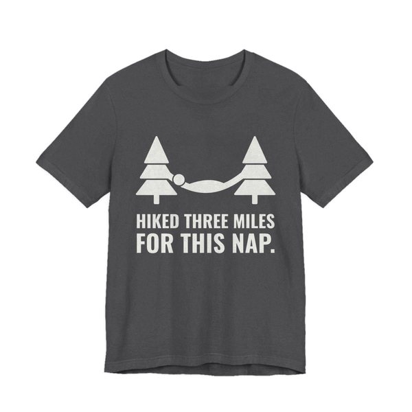 Dark Grey Heather t-shirt printed in off-white ink with a hammock between two pine trees and the words “Hiked Three Miles for This Nap.”