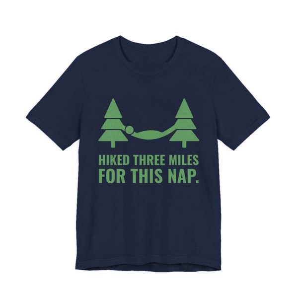 Navy t-shirt printed in pine green ink with a hammock between two pine trees and the words “Hiked Three Miles for This Nap.”