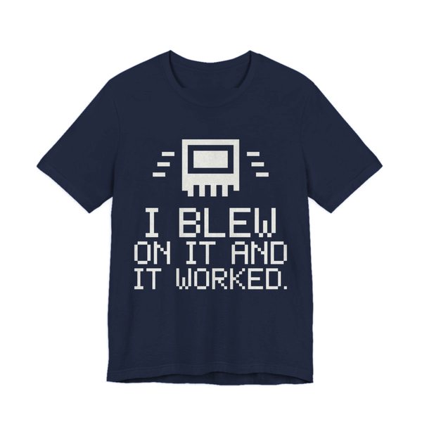 Navy t-shirt printed in off-white ink with a pixel-art cartridge and the words “I Blew on It and It Worked.” in a blocky pixel font