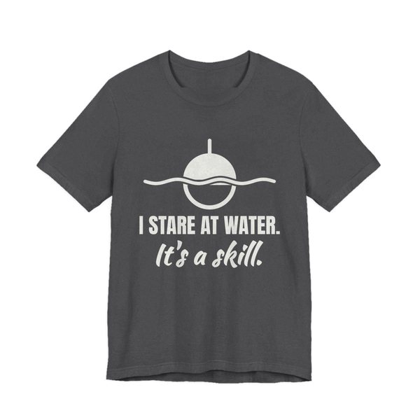 Dark Grey Heather t-shirt printed in off-white ink with a bobber on wavy water and the words “I Stare at Water. It's a Skill.”