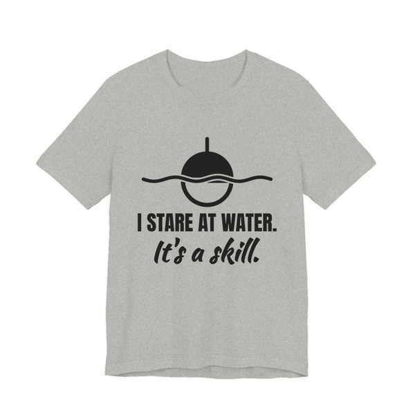 Athletic Heather t-shirt printed in dark ink with a bobber on wavy water and the words “I Stare at Water. It's a Skill.”