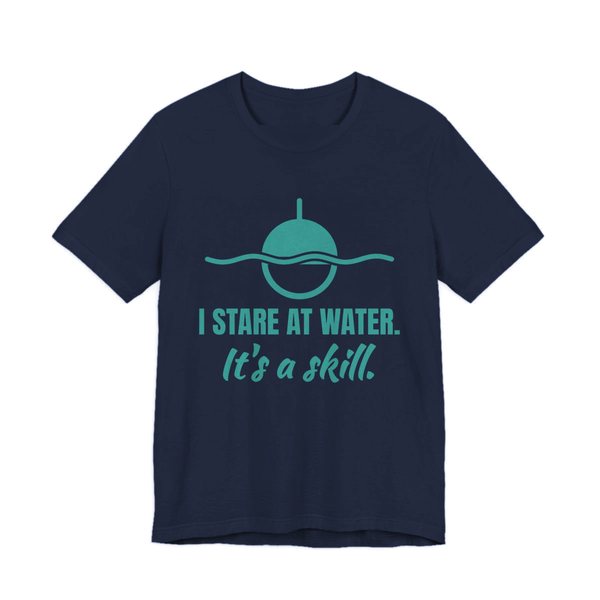 Navy t-shirt printed in teal ink with a bobber on wavy water and the words “I Stare at Water. It's a Skill.”