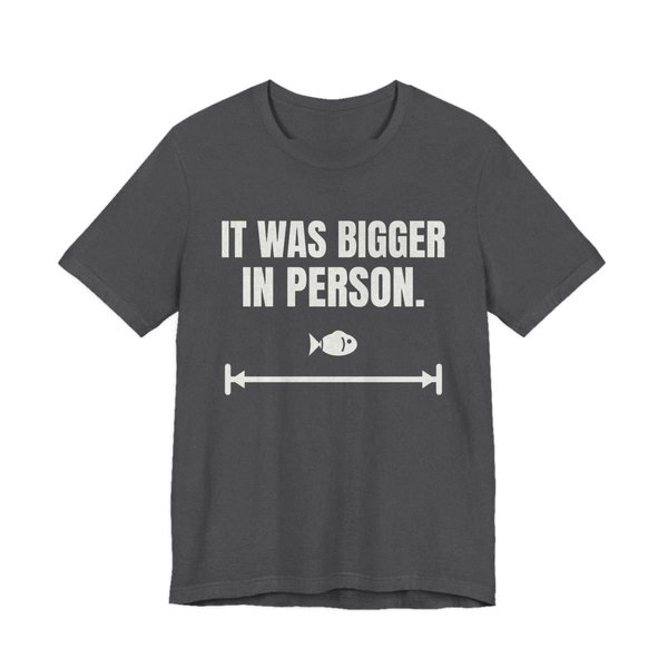 Dark Grey Heather t-shirt printed in off-white ink with a small fish on a long measuring arrow and the words “It Was Bigger in Person.”