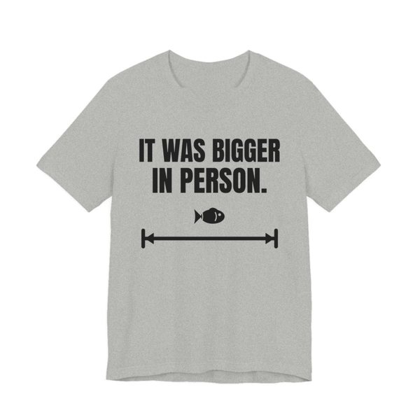 Athletic Heather t-shirt printed in dark ink with a small fish on a long measuring arrow and the words “It Was Bigger in Person.”