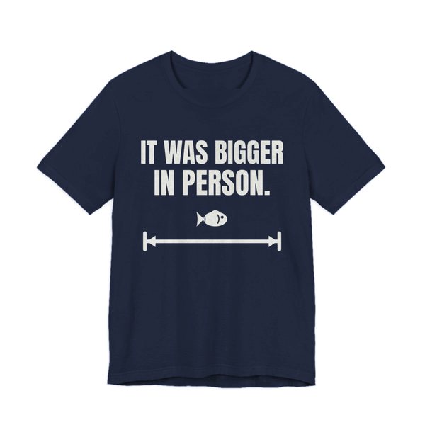 Navy t-shirt printed in off-white ink with a small fish on a long measuring arrow and the words “It Was Bigger in Person.”