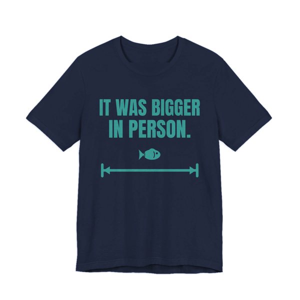 Navy t-shirt printed in teal ink with a small fish on a long measuring arrow and the words “It Was Bigger in Person.”