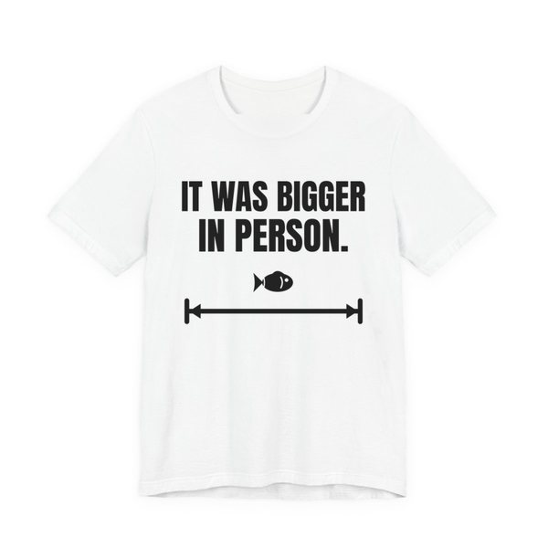 White t-shirt printed in dark ink with a small fish on a long measuring arrow and the words “It Was Bigger in Person.”