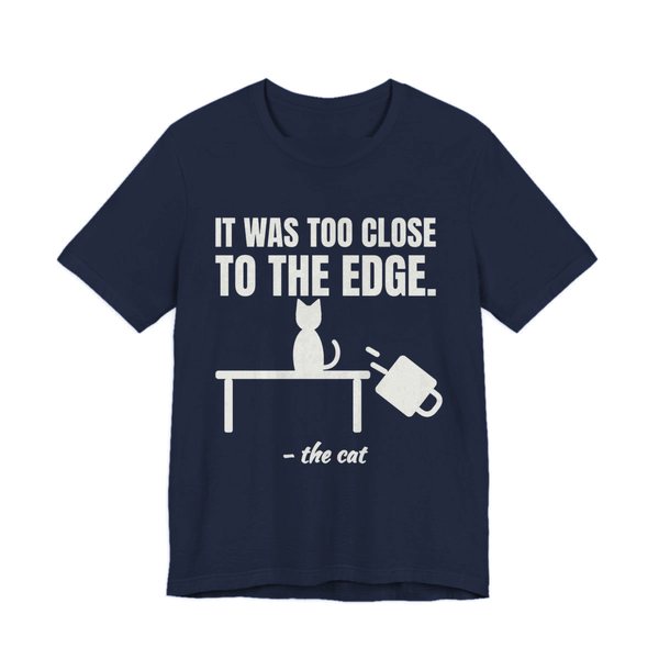 Navy t-shirt printed in off-white ink with a cat on a table, a falling mug and the words “It Was Too Close to the Edge.”