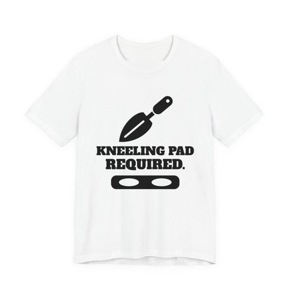 White t-shirt printed in dark ink with a trowel, a kneeling pad and the words “Kneeling Pad Required.”