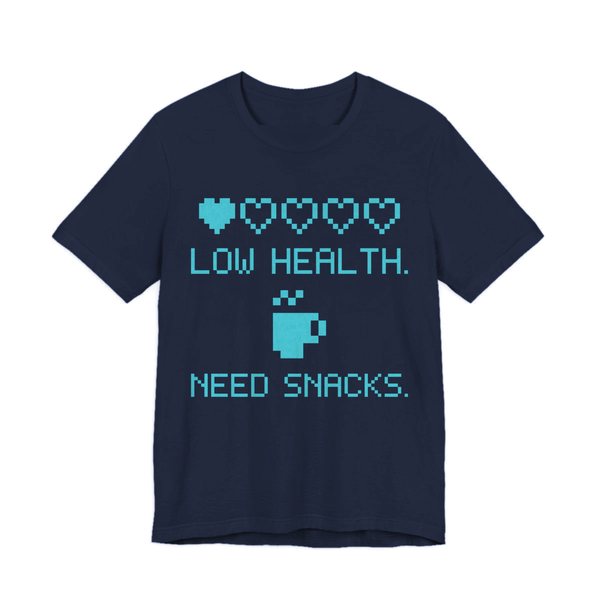 Navy t-shirt printed in cyan ink with a row of pixel hearts, a pixel mug and the words “Low Health. Need Snacks.”