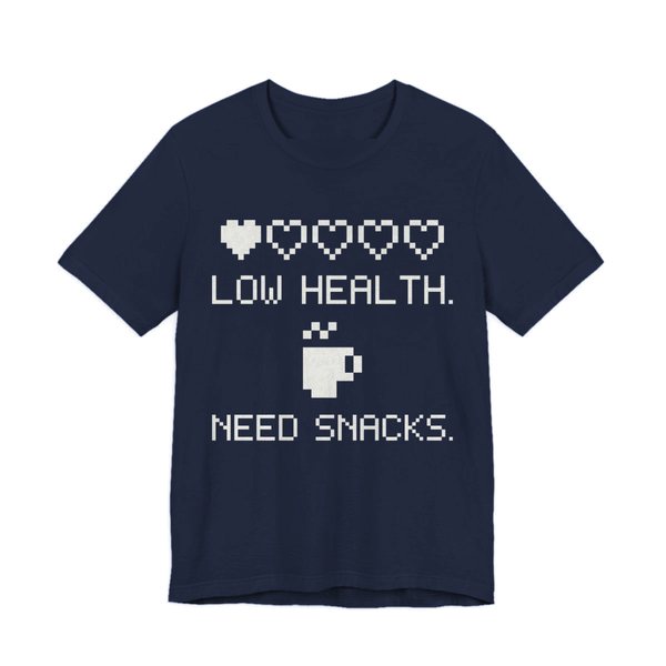 Navy t-shirt printed in off-white ink with a row of pixel hearts, a pixel mug and the words “Low Health. Need Snacks.”