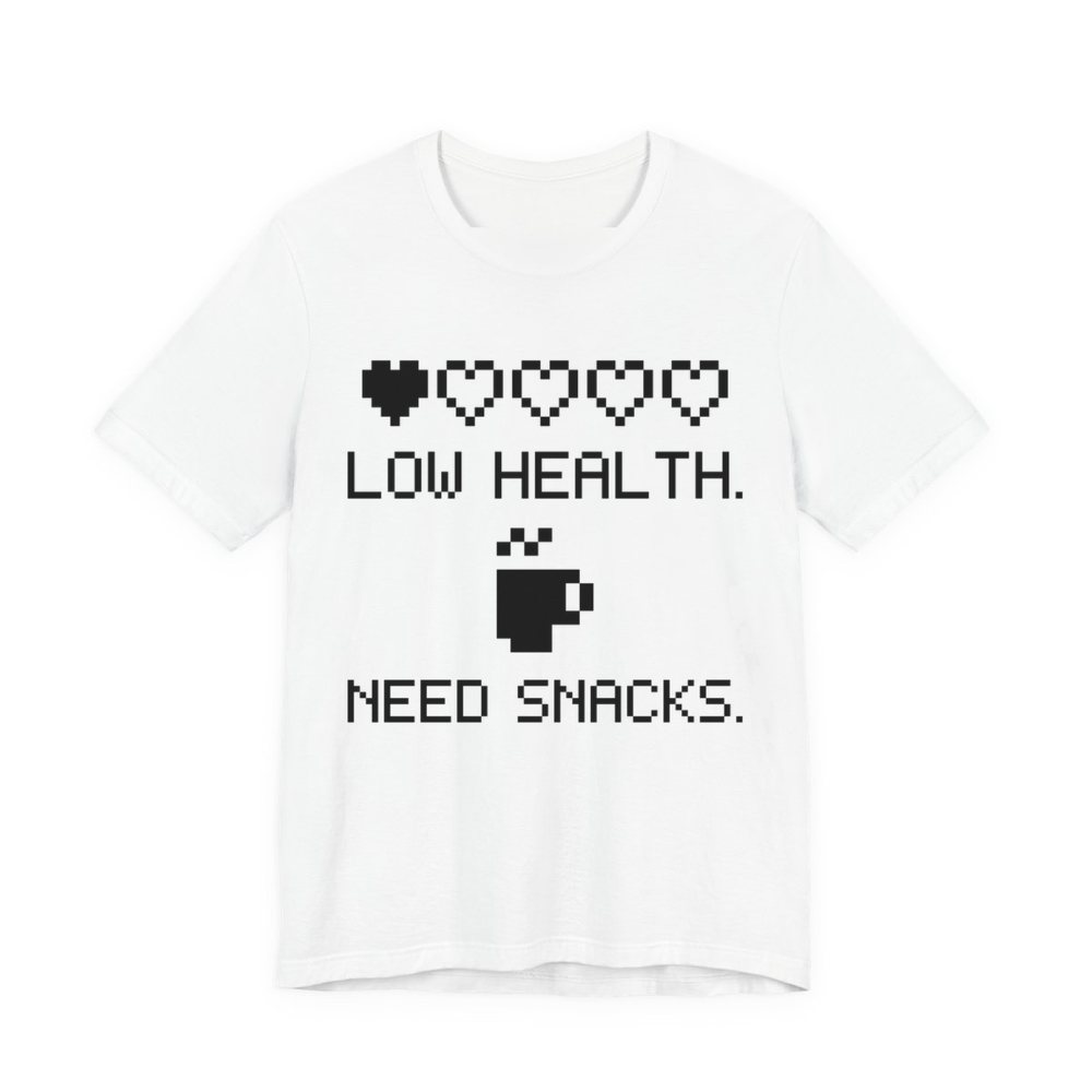 White t-shirt printed in dark ink with a row of pixel hearts, a pixel mug and the words “Low Health. Need Snacks.”