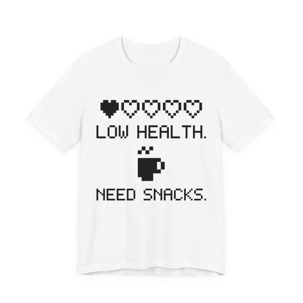 White t-shirt printed in dark ink with a row of pixel hearts, a pixel mug and the words “Low Health. Need Snacks.”